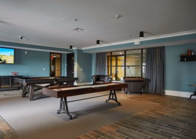 The resident lounge at The Winston at Lyndhurst Apartments, featuring seating, a billiards table, a shuffleboard table, and a spacious entertainment area with a large TV.