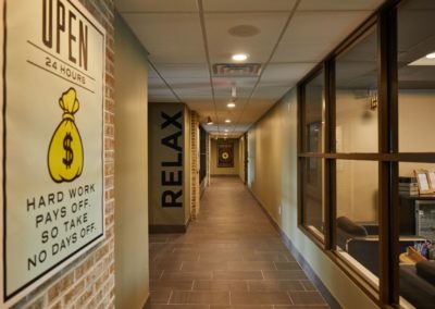 A hallway at The Winston at Lyndhurst Apartments featuring brick and glass accents, and wall art. The space has a contemporary design with signage that reads "RELAX" and "SUCCESS," creating an inviting and inspiring atmosphere for residents.